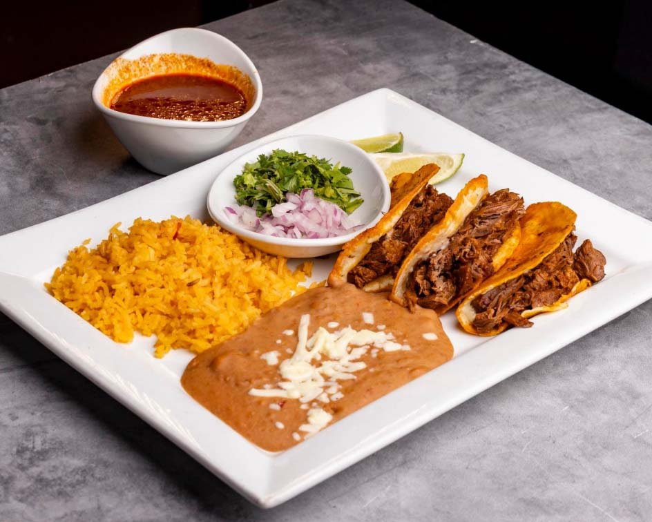 a dish of a certain kind of tacos with beans, rice, and other sides